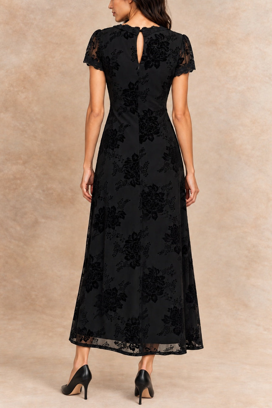 Bérénice black floral dress with lace-trimmed V-neck and short sleeves, back view on Inès with black heels.