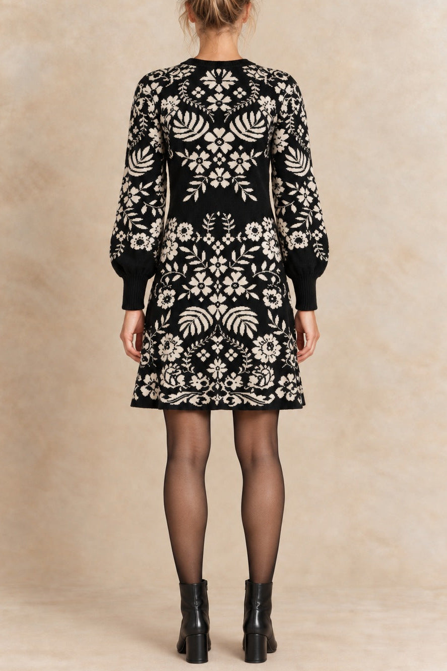 Léonie black and ivory botanical knit dress back view with semi-opaque tights and black ankle boots.