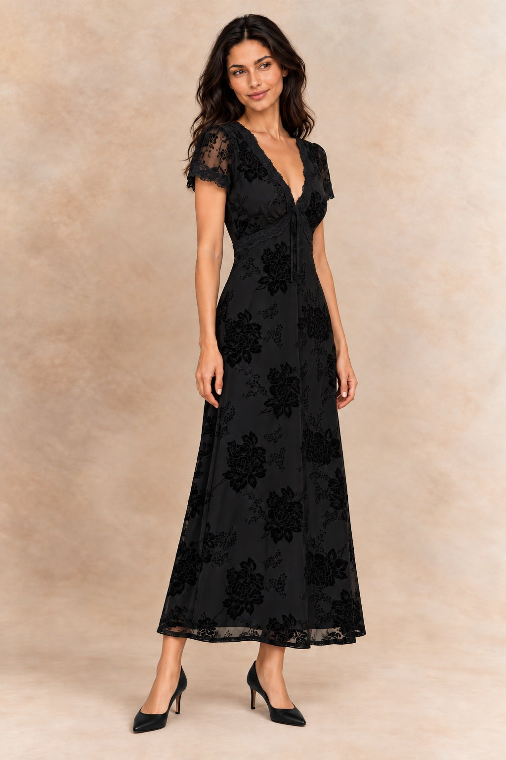 Bérénice black floral dress with lace-trimmed V-neck and short sleeves, three-quarter view on Inès with black heels.